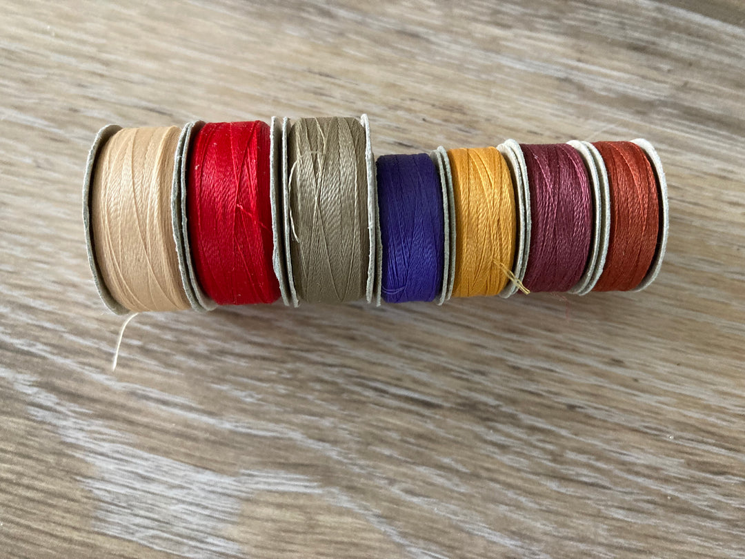 7 assorted colors of the Bottom Line L-style and M-style bobbins